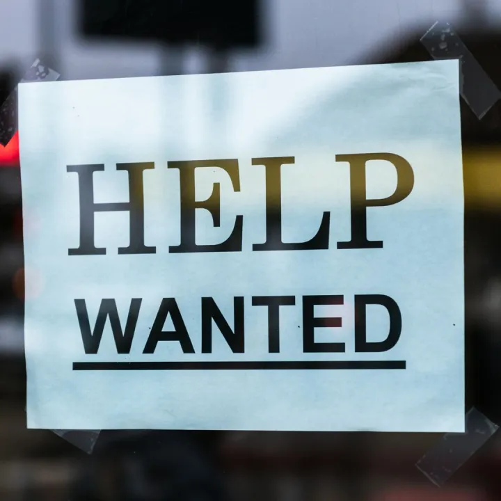 Close-up of a Help Wanted sign taped to a glass