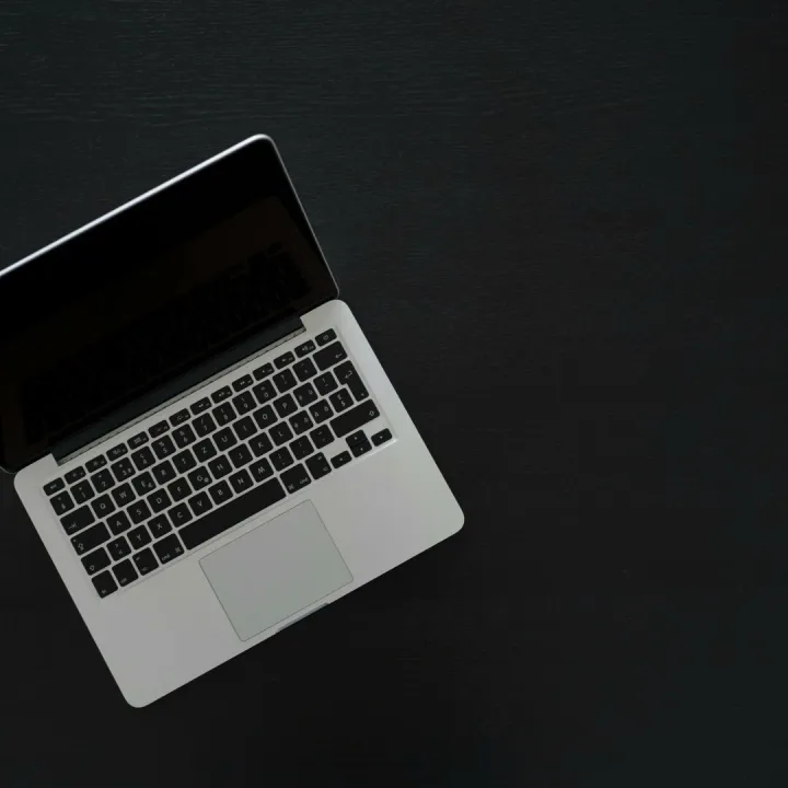 Overhead view of a MacBook laptop on a dark desk, showcasing modern technology and minimalism.