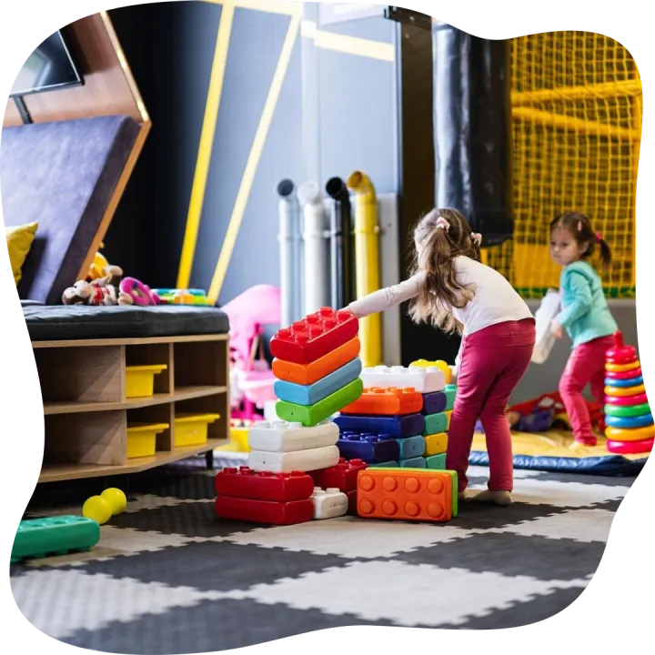 Two sisters playing at kids play center while build with col