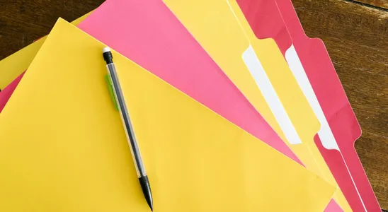 Colorful folders and pen arranged on a wooden