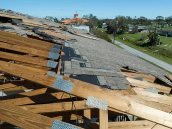 Damaged house roof with missing shingles after hurricane Ian