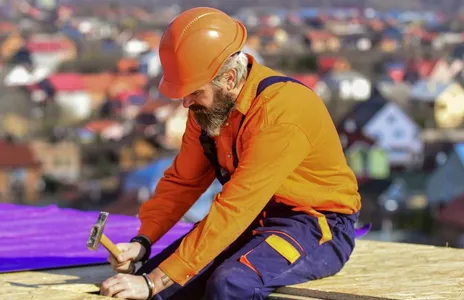 Roofer worker in special protective work wear new roof under