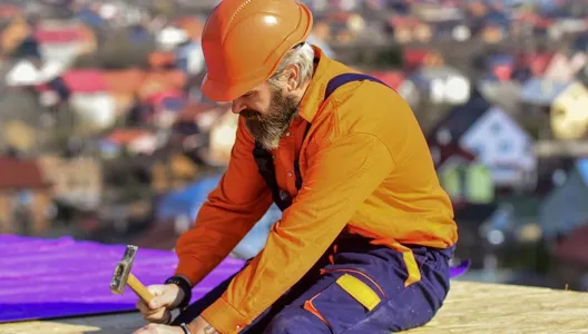 Roofer worker in special protective work wear new roof under