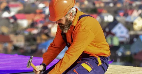 Roofer worker in special protective work wear new roof under