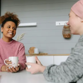 Two women share a joyful coffee moment at home