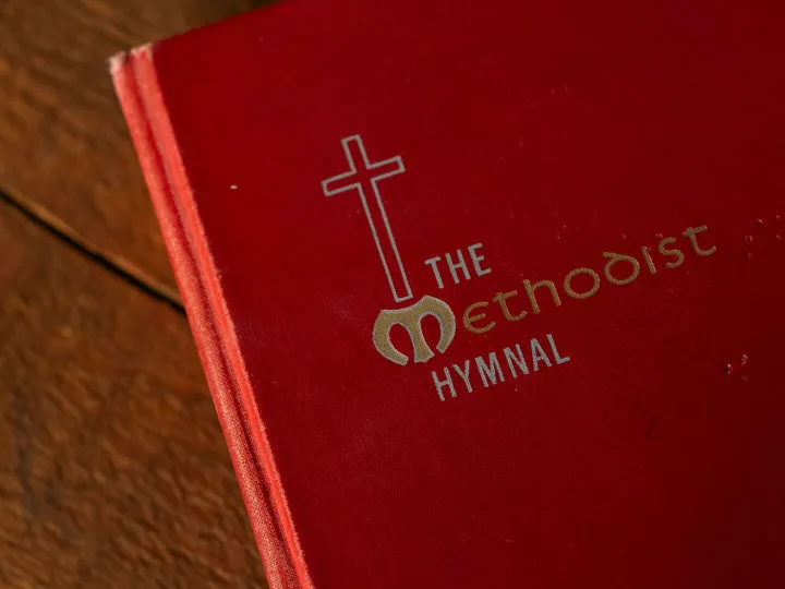 A Methodist hymn book resting on a wooden table