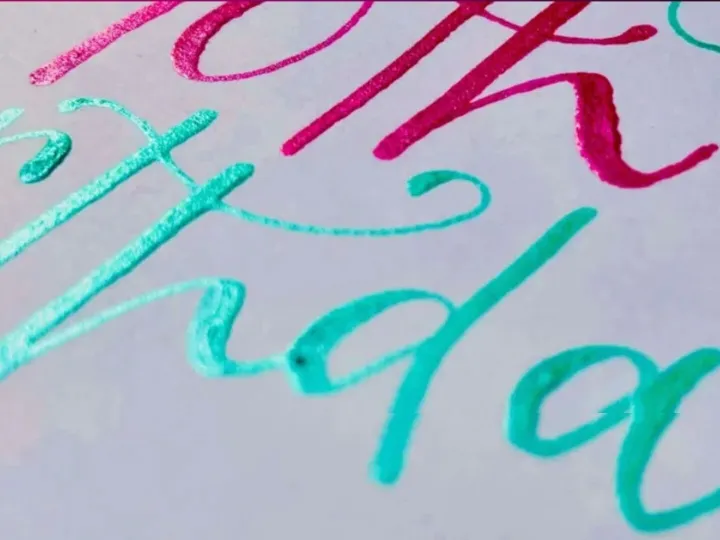 Turquoise and pink brush lettering with hand drawn flowers on a birthday card