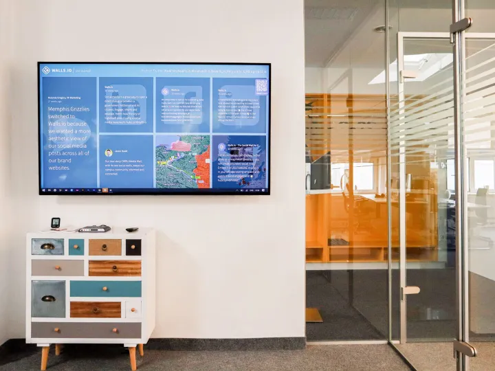 A wall-mounted screen displaying information slides in a bright foyer