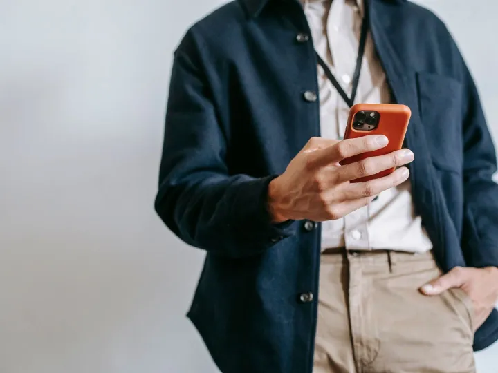 A man wearing a lanyard and name badge using his smartphone