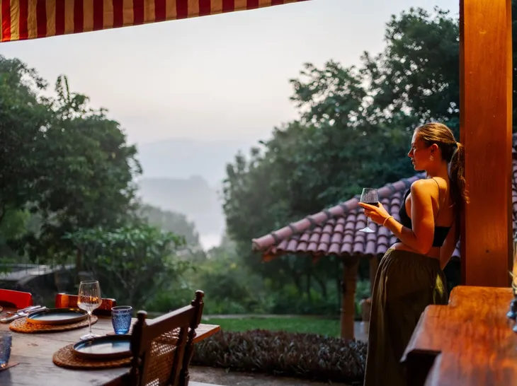 A guest with a glass of wine at the veranda rail at Peacock Hill Sigiriya