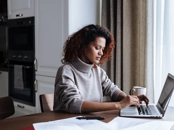 A council clerk working on a laptop at a kitchen table with paperwork