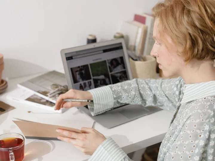 Church administrator working at a laptop with a notebook and a cup of tea