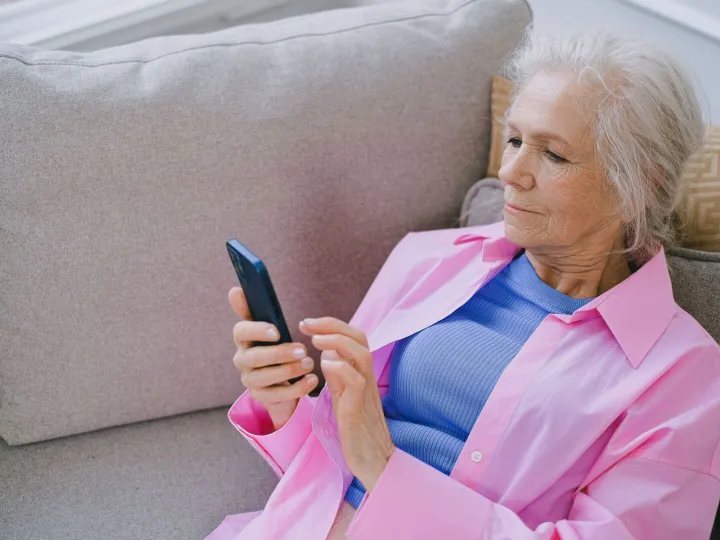 Older woman reading church news on her smartphone at home