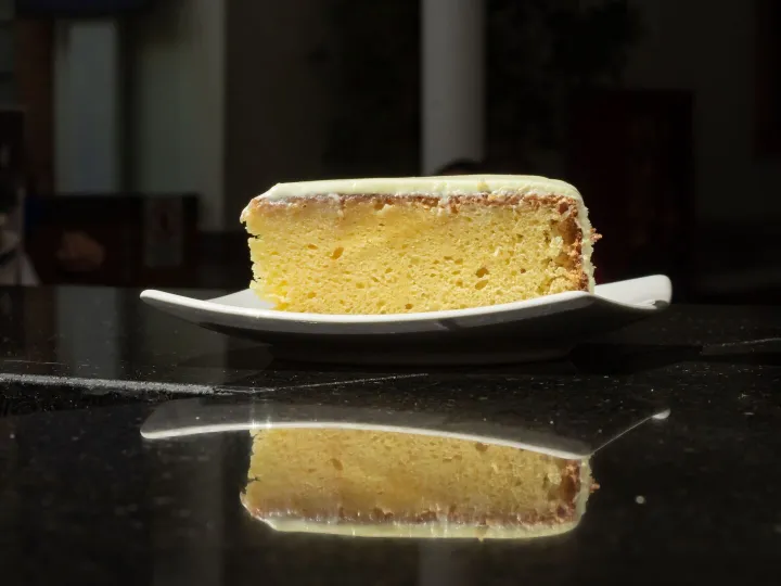 A fresh slice of lemon cake on a white plate