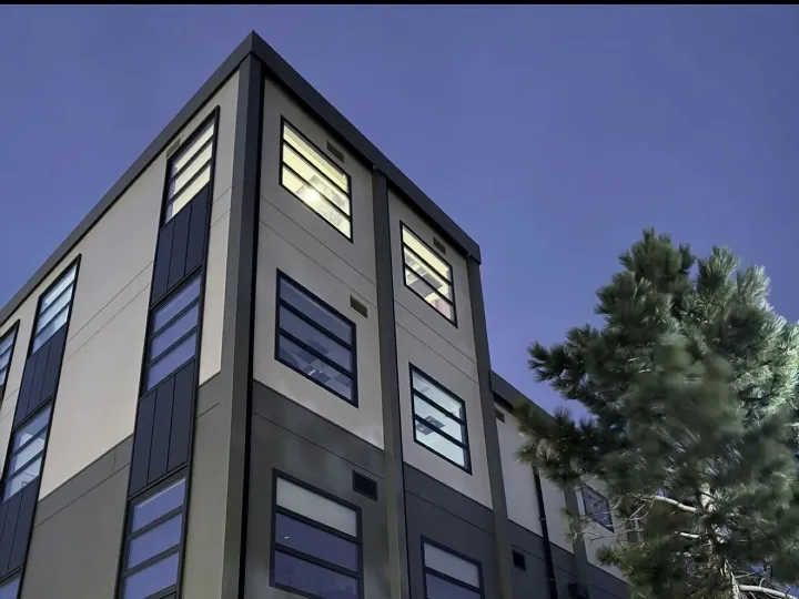 Multi-storey modular building with grey and white cladding photographed at dusk