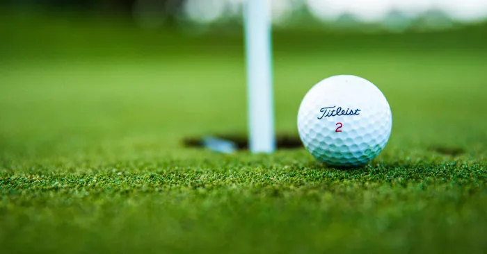 Close-up photo of a golf ball near the hole.