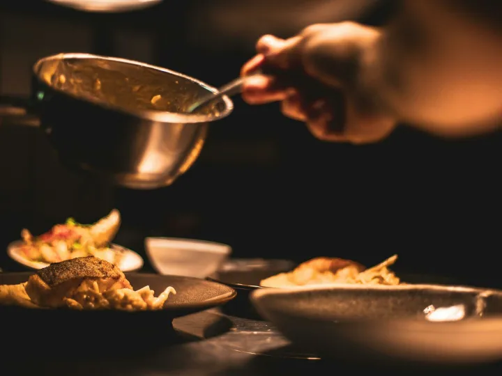 A chef plating a dish in a dimly lit restaurant kitchen