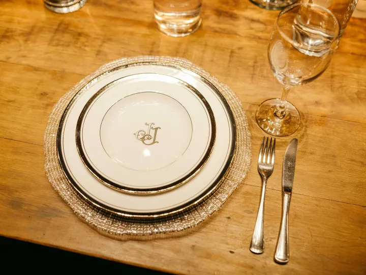 A monogrammed place setting on a wooden dining table