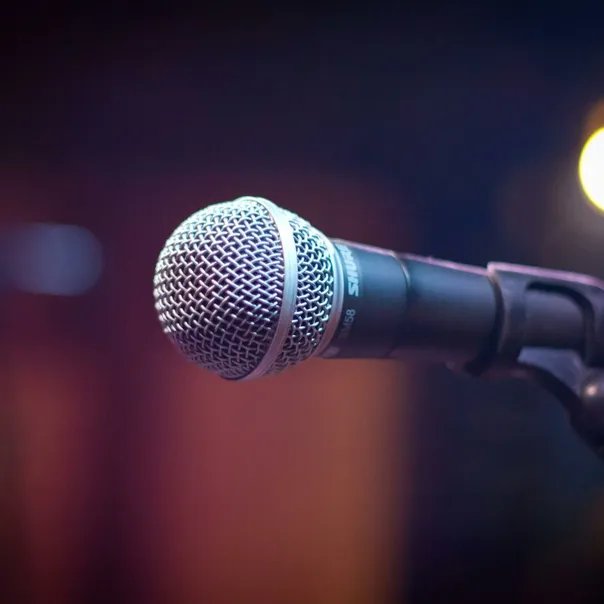 Dynamic microphone on stand with blurred stage lights in background.