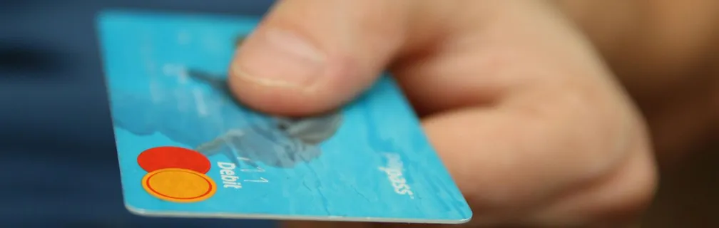A close-up shot of a hand offering a blue debit