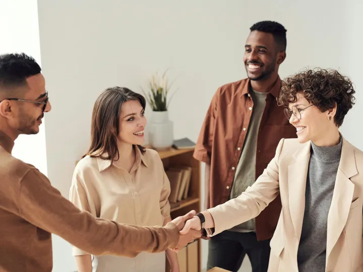 Four colleagues smiling and shaking hands in a bri