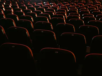 Rows of empty red seats in a dimly lit movie theater, showcasing a cinema environment.