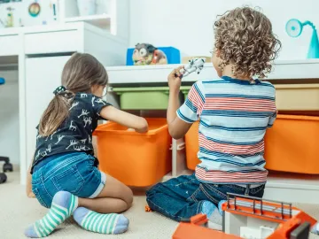 Two kids playing with toys and colorful bins in a