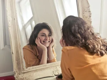 A cheerful woman smiles at her reflection in a