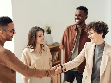 Four colleagues smiling and shaking hands in a bri