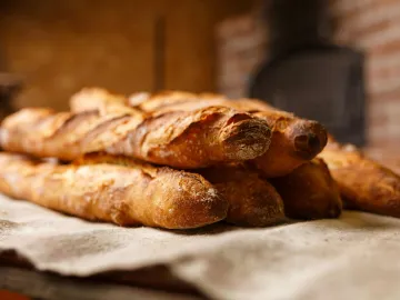 Warm, freshly baked rustic baguettes stacked in a 