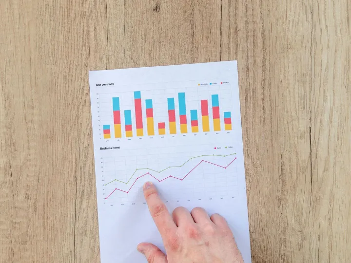 A hand points to colorful business charts and grap