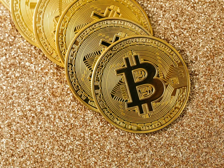 Golden Bitcoin coins arranged on a sparkling glitter surface, symbolizing cryptocurrency and wealth.