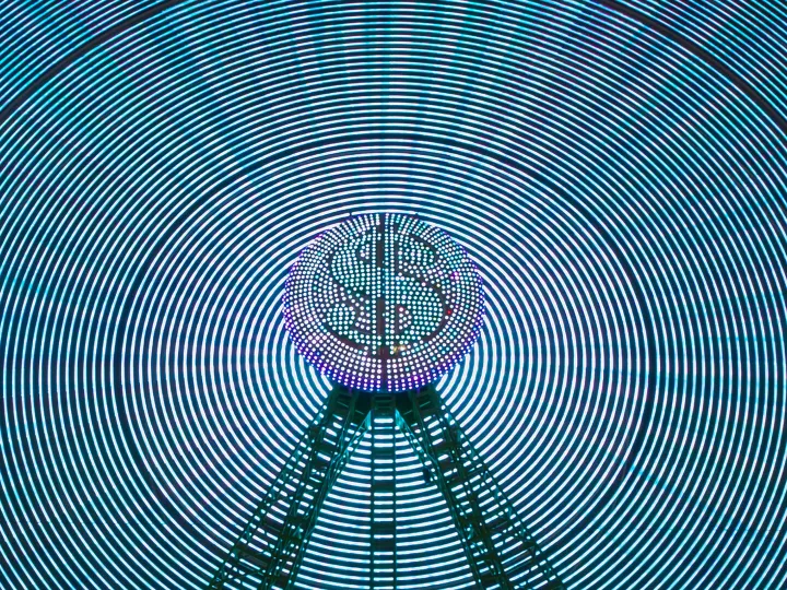 Abstract image of a digital dollar sign surrounded by neon concentric circles, representing fintech innovation and defence funding