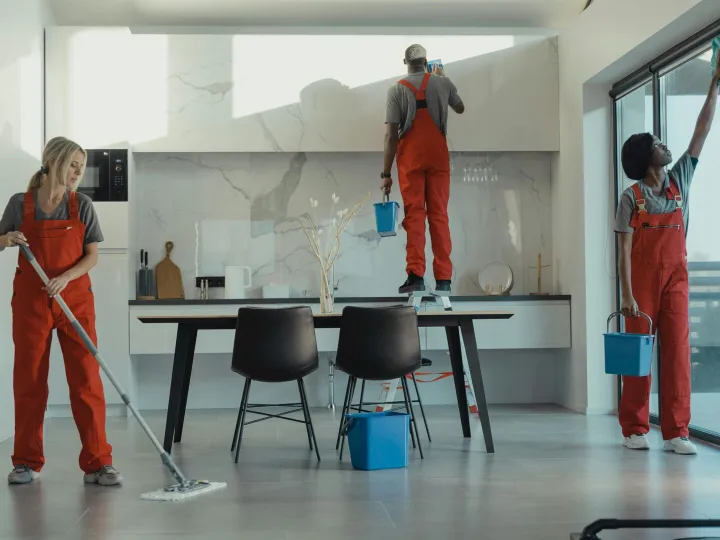 Group of cleaners in red uniforms mopping and wipi
